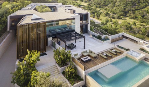 luxury smart home featuring a hot tub, hanging chair, couch, and floor to ceiling windows overlooking the ocean