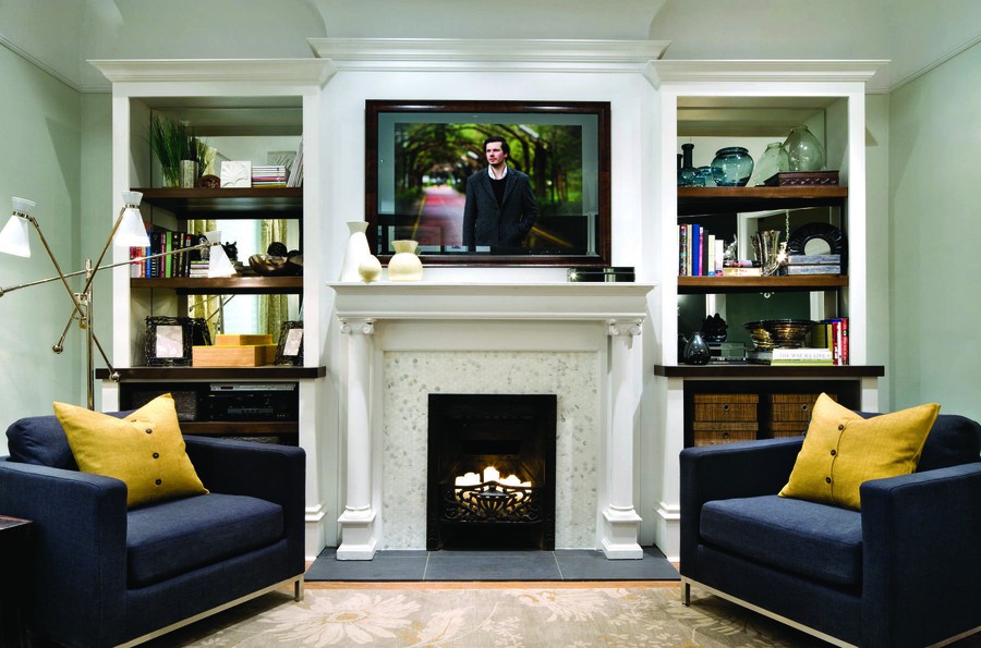 smart mirror TV installed above a fireplace mantle, with two living room chairs on either side