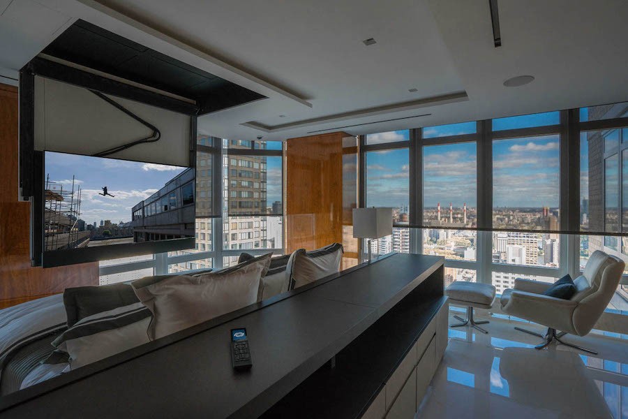 living room with hidden TV coming down from ceiling and floor-to-ceiling windows with automated shades 