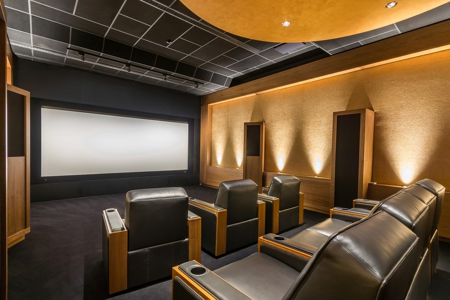 A custom home theater with golden walls and black floors and ceiling.