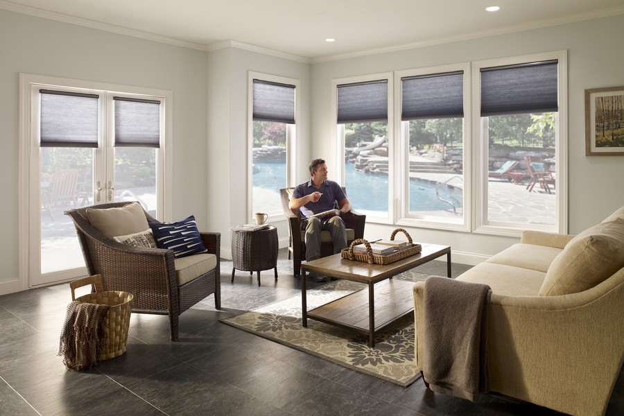 Motorized shades ina  casual, beachy living room, with a pool right outside the window.