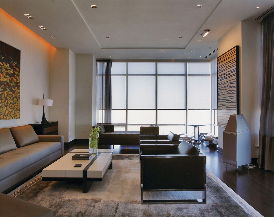 Modern living room with sleek furniture and floor-to-ceiling windows with motorized shades and drapes