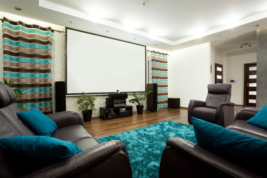 A home theater with a blue rug and leather chairs.