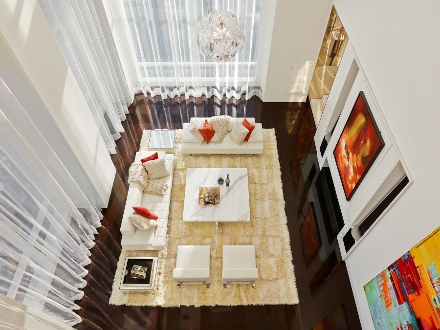 The bird’s eye view of a living room with vibrant paintings and diffuse sunlight.